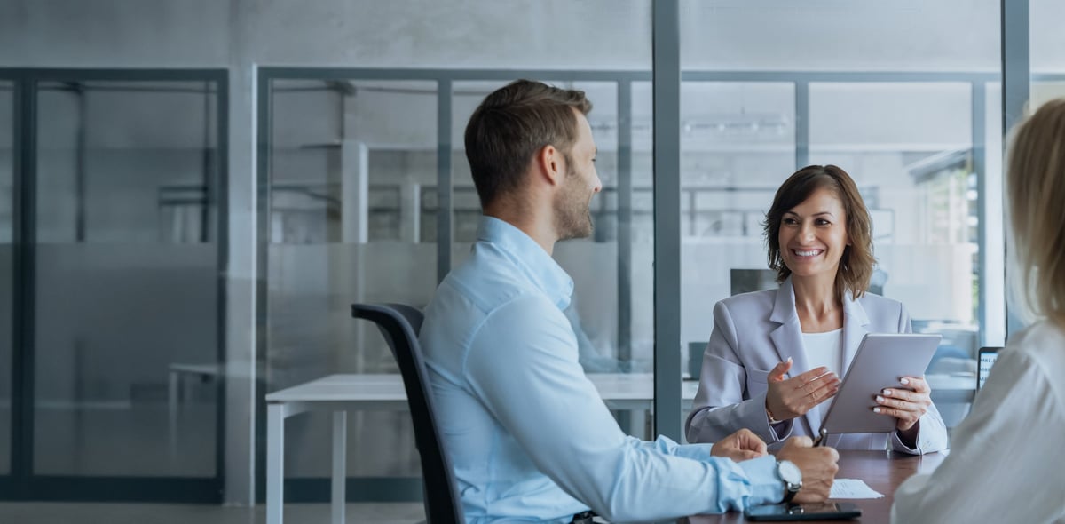 Business mentor reviewing a project on a tablet with colleagues in a modern office